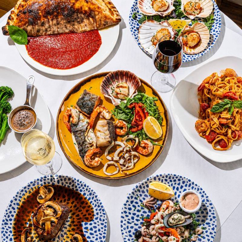 A table of seafood, calzone, steak and pasta from above